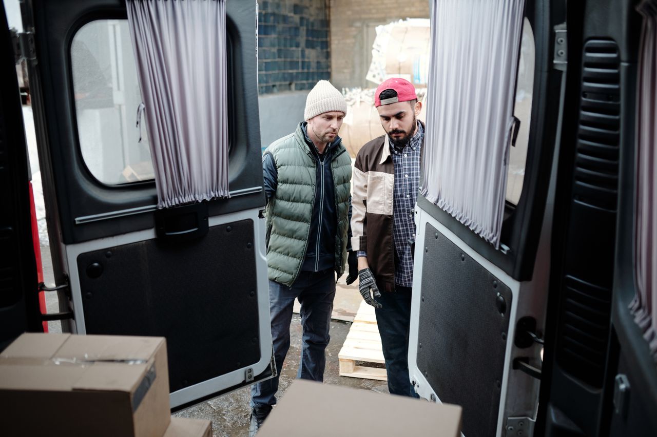 Home Two delivery workers load parcels into a van, focusing on efficiency and teamwork.